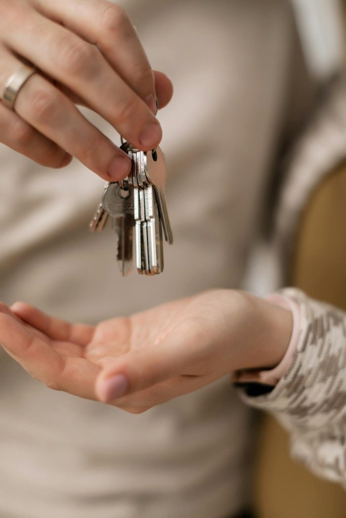 A close-up photograph of hands exchanging keys, symbolizing new home ownership.